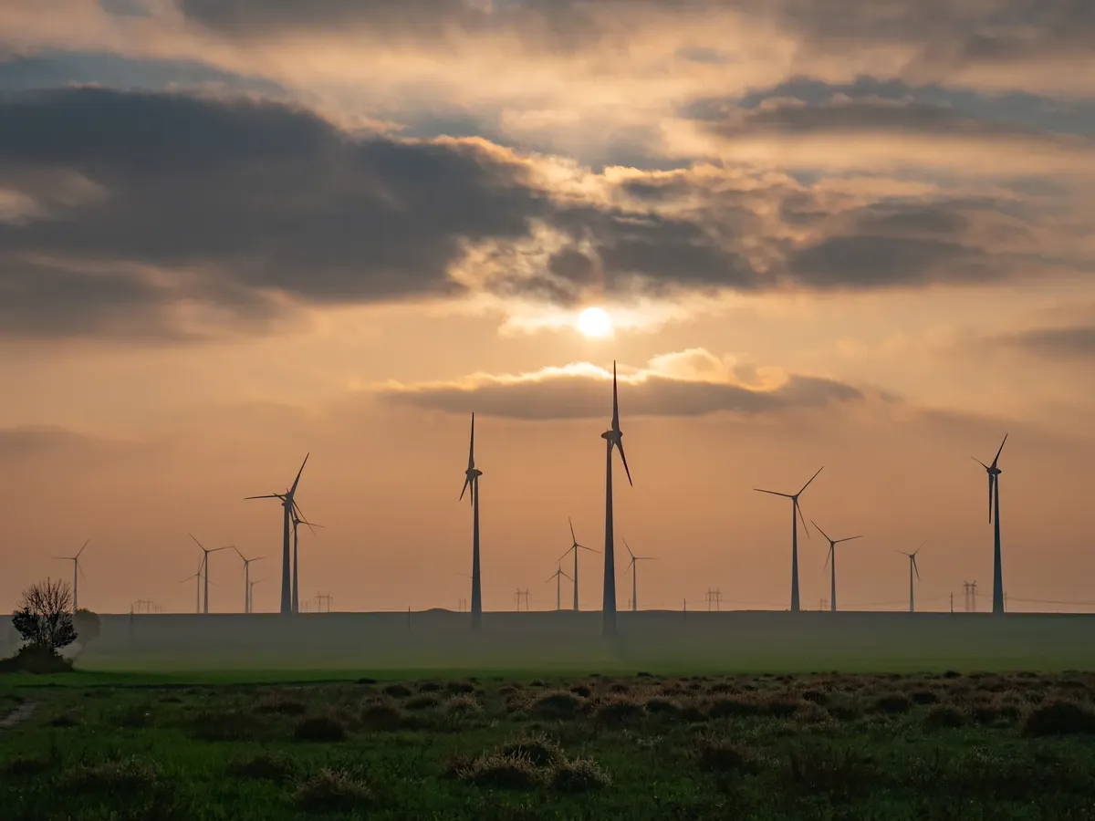 Majestic wind turbines in a Romanian field at sunset, symbolizing renewable energy.