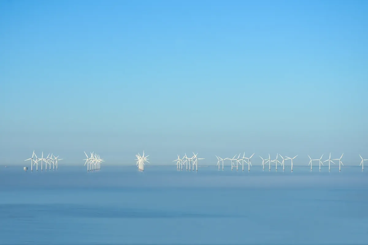 Serene offshore wind turbines beneath a clear blue sky generating renewable energy.