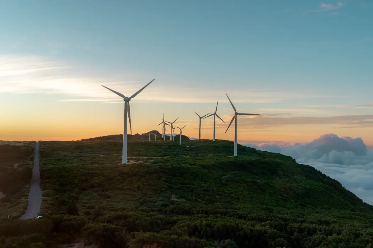 Scenic view of wind turbines on Madeira Island with vibrant sunset sky and lush landscape.