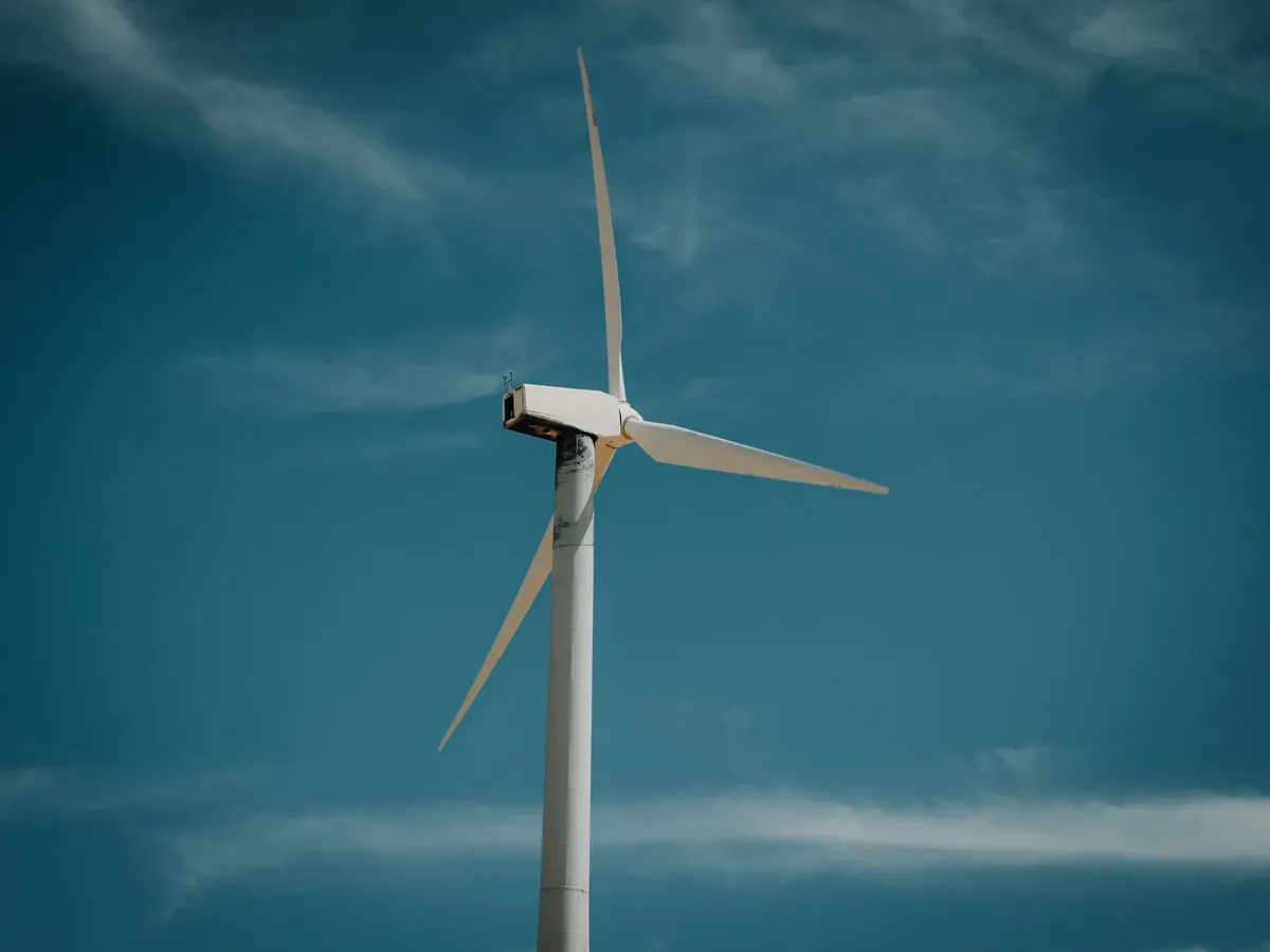 Wind turbine generating renewable energy under a clear blue sky, symbolizing sustainability.