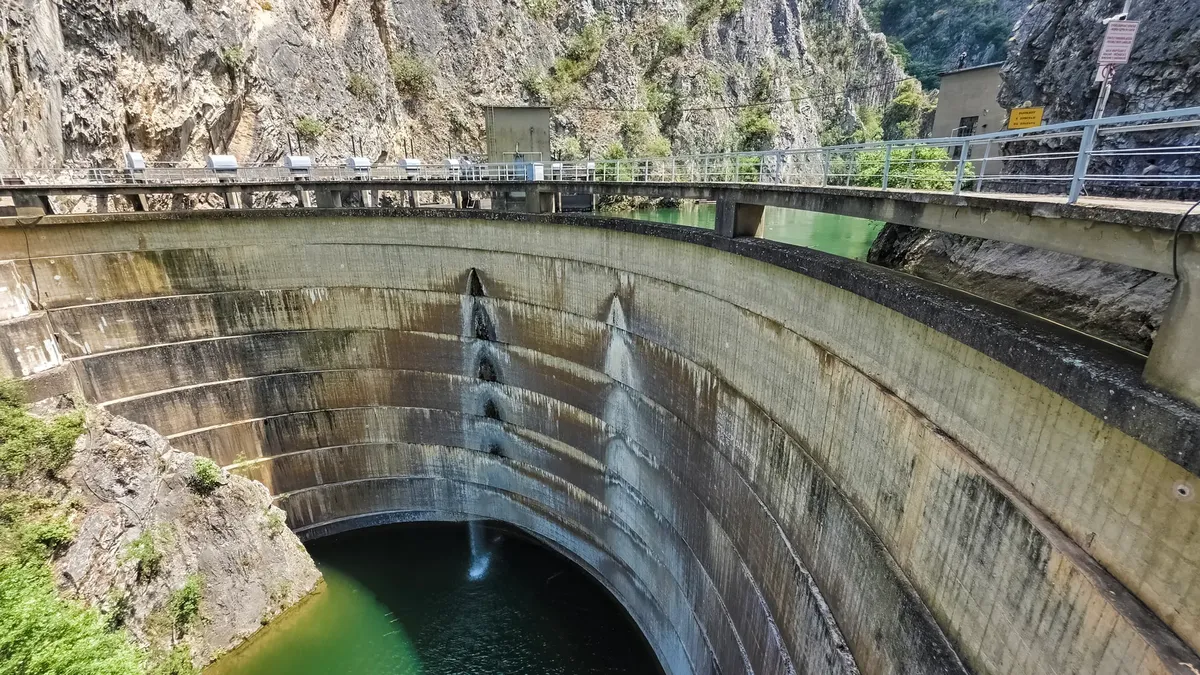 Scenic view of Vitok Dam spillway with water flowing in a gorge, showcasing engineering amidst nature.