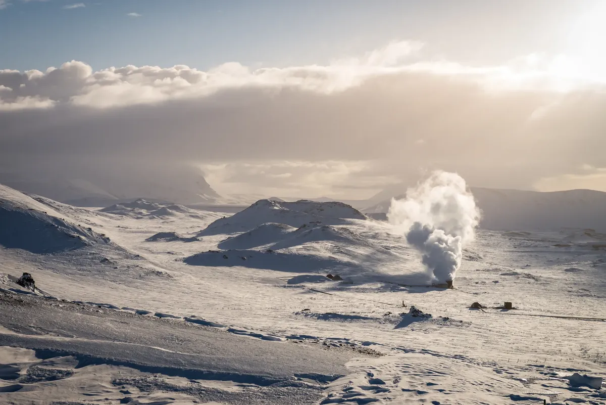 Tranquil winter landscape showcasing snow-covered hills under a dramatic sky with visible steam.
