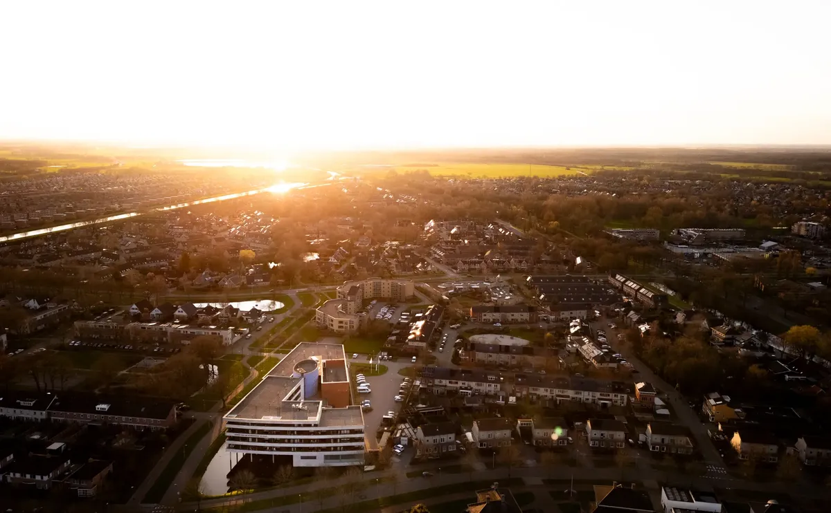 Drone aerial view of Hoogeveen, Netherlands, with warm sunset lighting across the townscape.